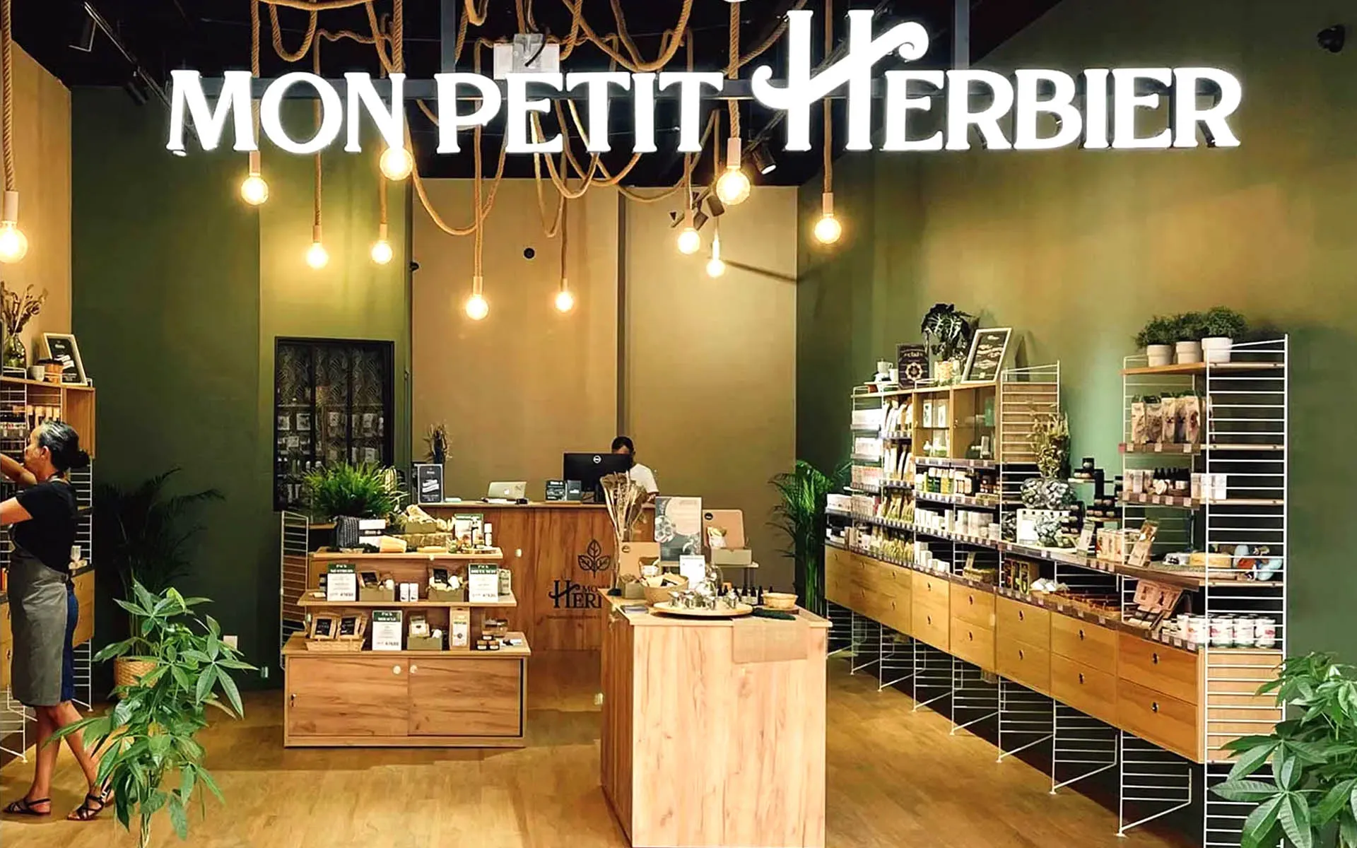 Comptoir en bois sous guirlande de corde et enseigne lumineuse.